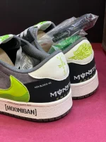 کتونی ترویس اسکات مانستر با طراحی خاص، لوگوی سبز مانستر و ترکیب رنگ جذاب مشکی و سفید.