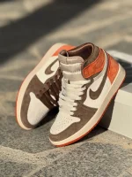 تصویر کتونی جردن 1 داستد کلی با طراحی منحصر به فرد و رنگ‌های خاکی و قرمز مایل به قهوه‌ای