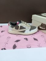 تصویر کتونی ایر جردن 1 ترویس اسکات ریورس موکا با رنگ‌بندی قهوه‌ای و سفید و لوگوی معکوس نایک