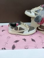 تصویر کتونی ایر جردن 1 ترویس اسکات ریورس موکا با رنگبندی قهوهای و سفید و لوگوی معکوس نایک