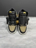 کتونی نایکی جردن 1 رترو های پالومینو با چرم مشکی و جیر قهوه‌ای در پس‌زمینه روشن