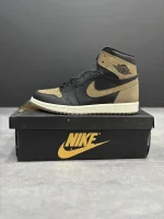 کتونی نایکی جردن 1 رترو های پالومینو با چرم مشکی و جیر قهوه‌ای در پس‌زمینه روشن