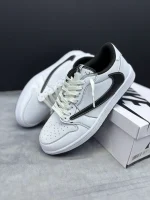 کتونی نایکی جردن 1 لـو ترویس اسکات فانتوم با جیر خاکستری روشن و سووش معکوس در پس‌زمینه روشن