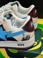 کتونی بیپ مارول راکت راکون بژ و مشکی با جزئیات آبی و قهوه‌ای در پس‌زمینه روشن