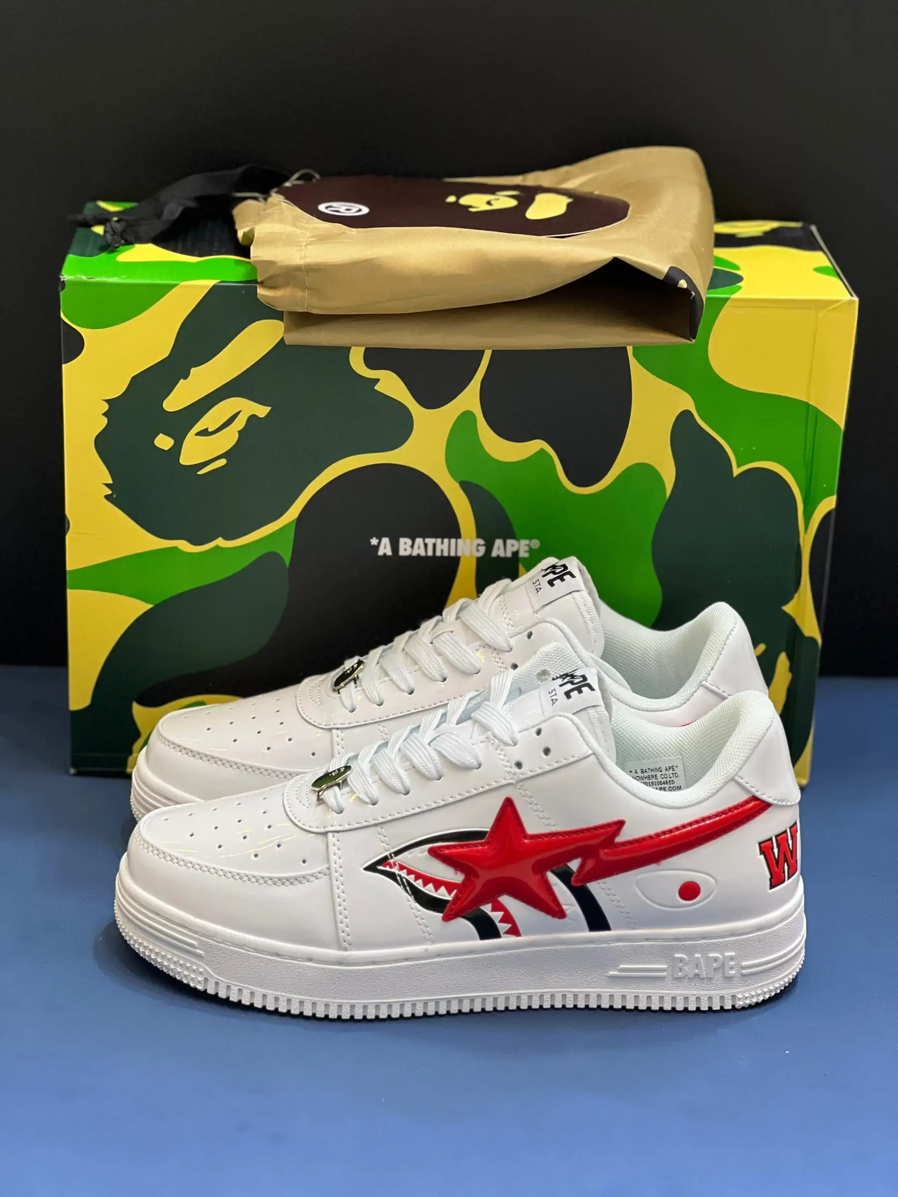 a-bathing-ape-bape-sta (3) کتونی بیپ شارک فیس سفید با طرح کوسه قرمز و مشکی در پسزمینه روشن