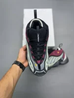 کتونی آدیداس اینتیمیدیشن پکر تک اینک با مش خاکستری و جیر مشکی در پس‌زمینه روشن