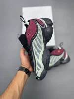 کتونی آدیداس اینتیمیدیشن پکر تک اینک با مش خاکستری و جیر مشکی در پس‌زمینه روشن