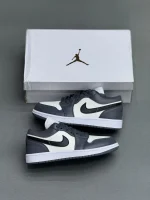 کتونی نایکی جردن 1 لـو متالیک سیلور با چرم خاکستری و درخشش نقره‌ای در پس‌زمینه روشن