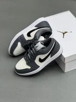 کتونی نایکی جردن 1 لـو متالیک سیلور با چرم خاکستری و درخشش نقره‌ای در پس‌زمینه روشن