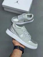 کتونی نایکی جردن 1 لـو متالیک سیلور با چرم خاکستری و درخشش نقرهای در پسزمینه روشن