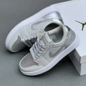 کتونی نایکی جردن 1 لـو متالیک سیلور با چرم خاکستری و درخشش نقره‌ای در پس‌زمینه روشن