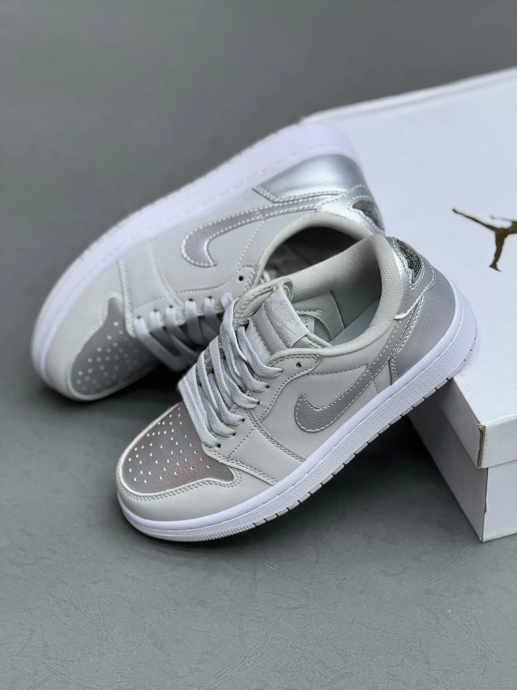 aj1-low-mettalic-silver کتونی نایکی جردن 1 لـو متالیک سیلور با چرم خاکستری و درخشش نقرهای در پسزمینه روشن