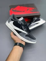 کتونی نایکی جردن 1 لـو ترویس اسکات خاکستری با چرم سفید و جیر خاکستری در پسزمینه روشن