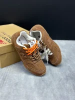 کتونی نیوبالانس میو میو قهوه‌ای با چرم و جیر در پس‌زمینه روشن