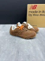 کتونی نیوبالانس میو میو قهوه‌ای با چرم و جیر در پس‌زمینه روشن