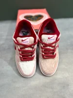 کتونی نایکی اس‌بی دانک لـو استرنج لاو با مخمل صورتی و جیر قرمز در پس‌زمینه روشن