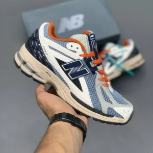 کتونی نیوبالانس 1906R بلک‌تاپ میندفول گری با مش خاکستری و روکش‌های جیر در پس‌زمینه روشن