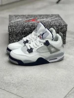 کتونی نایکی جردن 4 میدنایت نِیوی با چرم سفید و روکش‌های آبی تیره در پس‌زمینه روشن