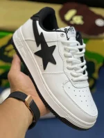 کتونی A Bathing Ape Bapesta x JJJJound وایت نوی با چرم سفید و روکش‌های آبی در پس‌زمینه روشن