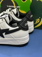 کتونی A Bathing Ape Bapesta x JJJJound وایت نوی با چرم سفید و روکش‌های آبی در پس‌زمینه روشن