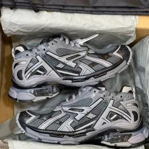 کتونی بالنسیاگا رانر دارک گری/بلک با مش خاکستری و روکش‌های تیره در پس‌زمینه روشن