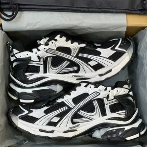 کتونی بالنسیاگا رانر مشکی سفید با مش تیره و روکش‌های سفید در پس‌زمینه روشن