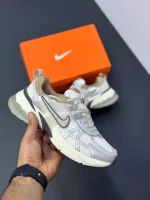 کتونی نایکی V2K Run اوروود براون با مش قهوهای و روکشهای شفاف در پسزمینه روشن