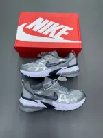 کتونی نایکی V2K Run گری/میدنایت نوی با مش خاکستری و روکش‌های آبی در پس‌زمینه روشن