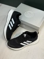 کتونی آدیداس رانفالکن 5 بلک وایت با مش مشکی و روکش‌های سفید در پس‌زمینه روشن