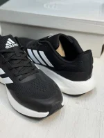 کتونی آدیداس رانفالکن 5 بلک وایت با مش مشکی و روکش‌های سفید در پس‌زمینه روشن