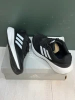 کتونی آدیداس رانفالکن 5 بلک وایت با مش مشکی و روکش‌های سفید در پس‌زمینه روشن