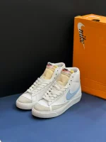 کتونی نایکی بلازر مید 77 وینتیج وایت اند بلو با چرم سفید و سووشهای آبی در پسزمینه روشن