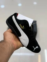 کتونی پوما اسپیدکت بلک با سُئد مشکی و لوگوی گربه در پسزمینه روشن