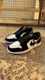 کتونی نایکی جردن 1 لو پاندا با چرم مشکی و سووشهای سفید در پسزمینه روشن