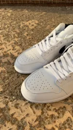 کتونی نایکی جردن 1 لو ریورس پاندا با چرم سفید و سووشهای مشکی در پسزمینه روشن