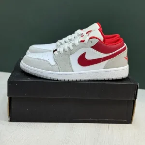 کتونی نایکی جردن 1 لو اسموک گری/رِد با چرم خاکستری و سووش‌های قرمز در پس‌زمینه روشن