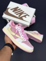 کتونی نایکی جردن 1 لو ترویس اسکات شای پینک با چرم سیل و سُئد صورتی در پسزمینه روشن